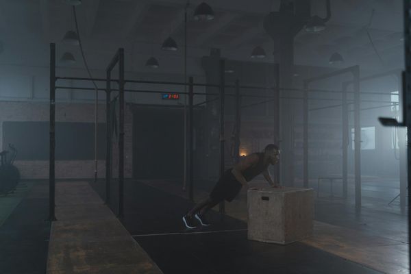 Man performing functional exercises in a dark atmospheric gym environment.